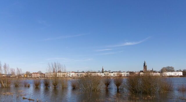 Weerbericht in Cuijk met natte weg bij station en donkere regenlucht boven het centrum